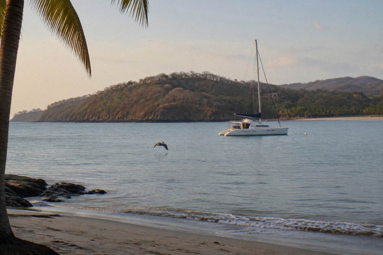 Catamaran at anchor in a calm Pacific bay near Tamarindo with wooded headlands in the background