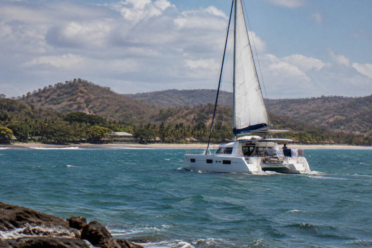 Catamaran sails along the Guanacaste coast near Tamarindo under a partly cloudy sky