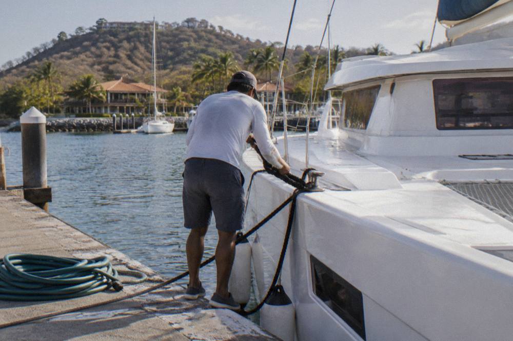 Crew member securing a mooring line on a catamaran deck near Tamarindo