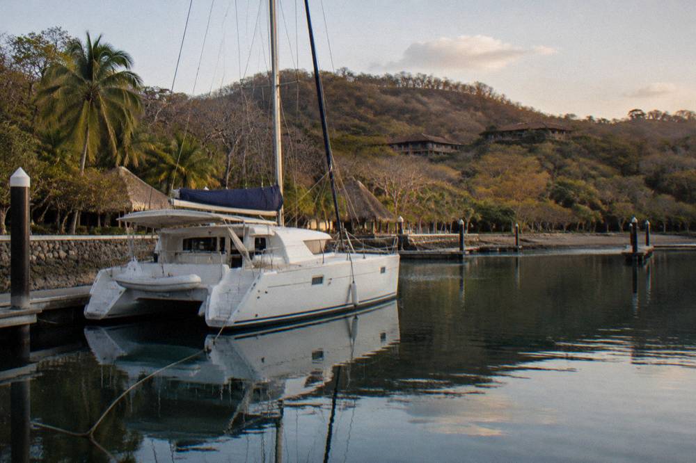 Private catamaran moored in a quiet bay on the Guanacaste coast with forested hills behind