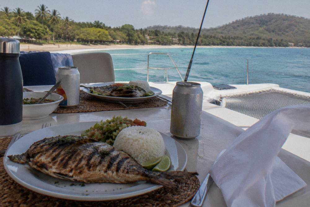 Grilled lunch and drinks laid out on a catamaran table during a cruise along the Guanacaste coast
