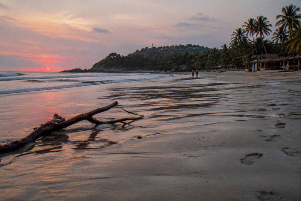 Orange and pink sunset sky over the Pacific horizon seen from an empty tropical beach