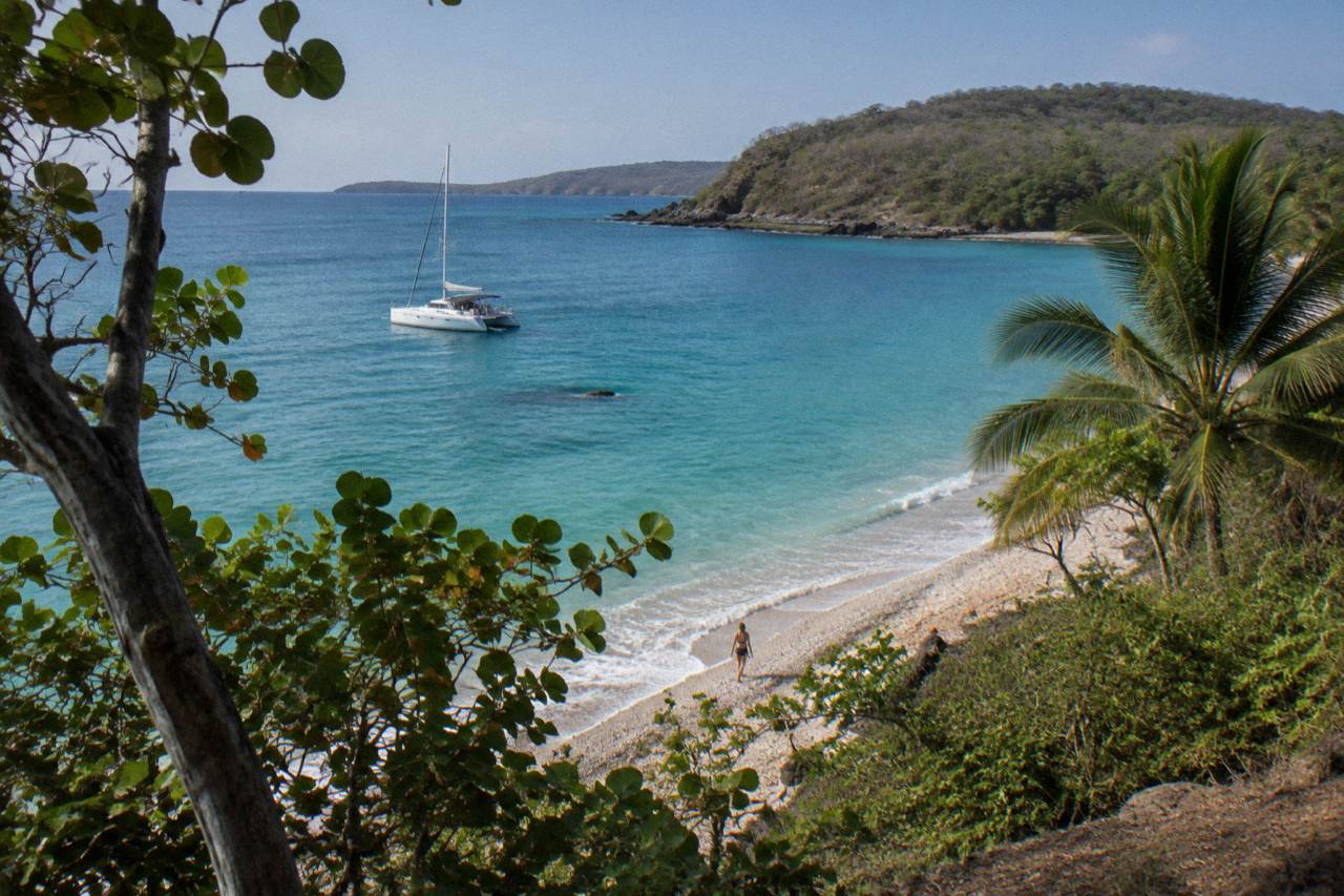 Catamaran anchored near a shell beach cove on the Guanacaste coast