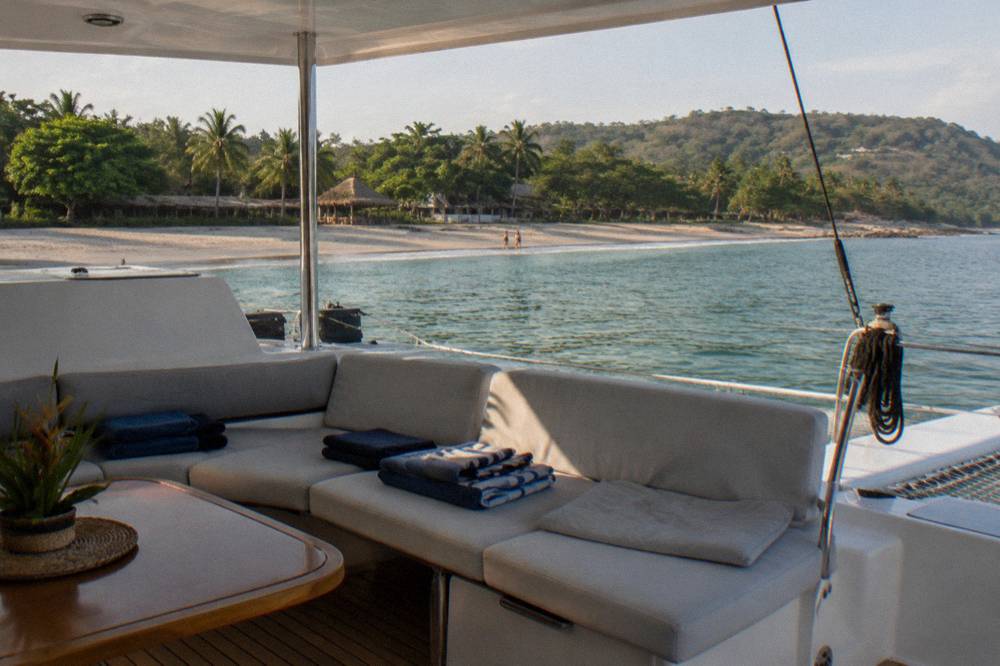A shaded catamaran deck with cushioned seating prepared for a private group