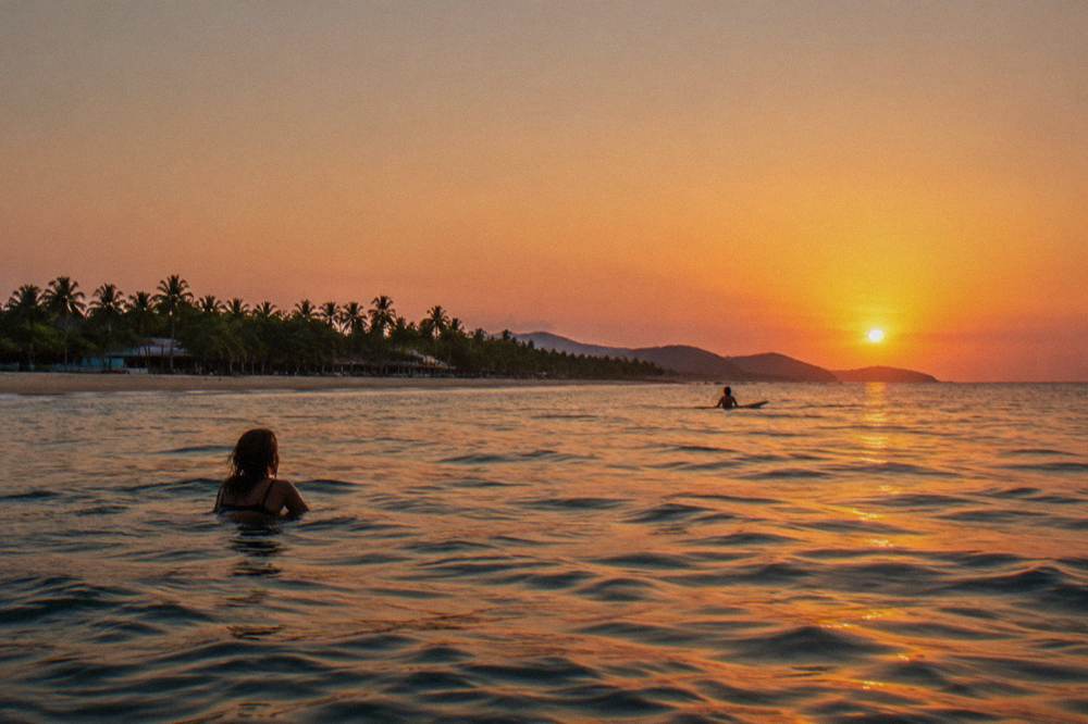 Sun setting over the Pacific horizon as seen from calm water near the shoreline
