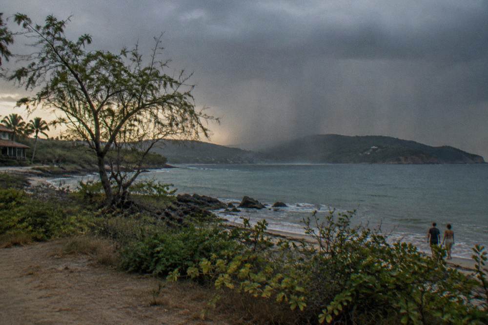 Waterfall of rain falling over dark green hills along the coast north of Tamarindo