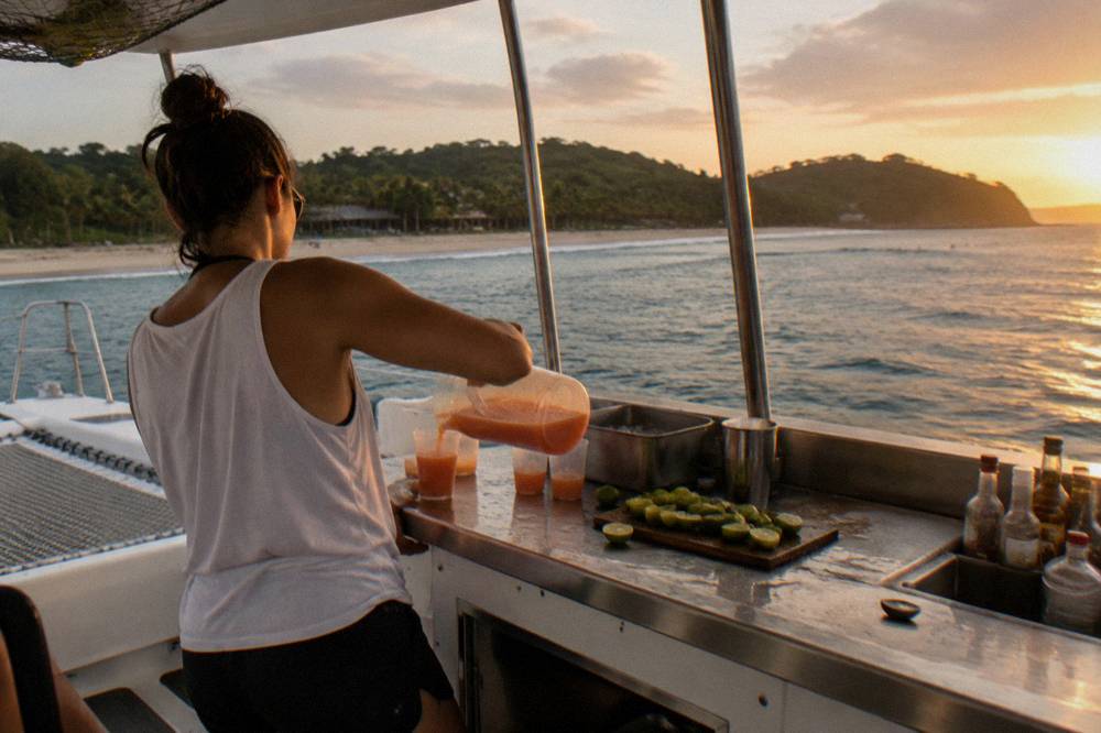 Crew member serving drinks at an outdoor catamaran bar counter