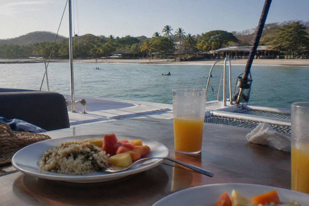 Table set with drinks and plated food on a catamaran deck