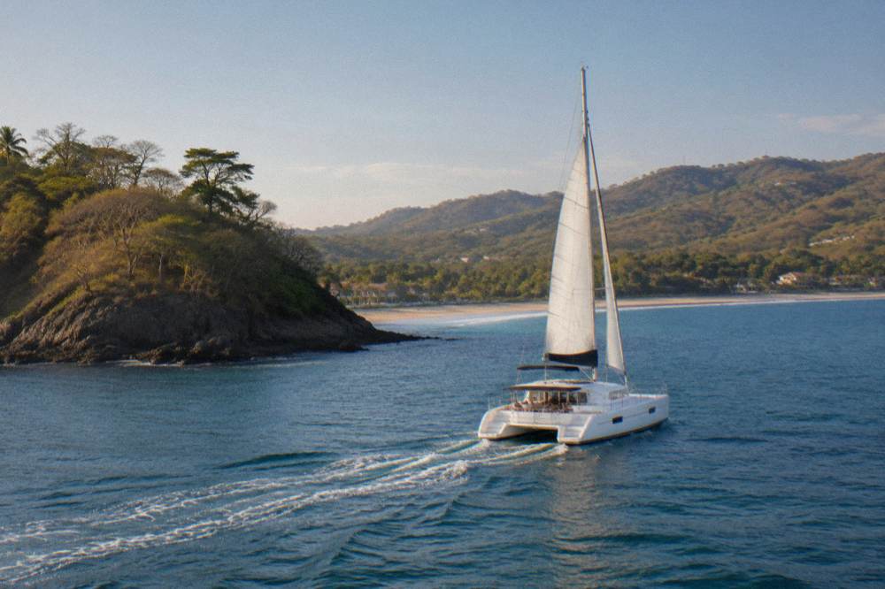 Private catamaran underway along the Guanacaste coastline with forested hills