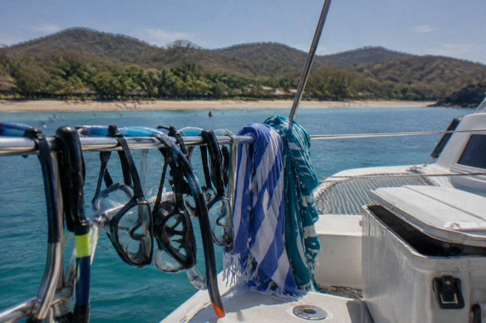 A catamaran deck with snorkel masks and towels drying in afternoon sun