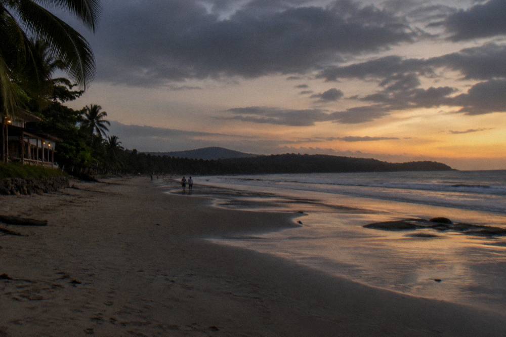 Wide empty beach at dusk with gentle surf and darkening sky