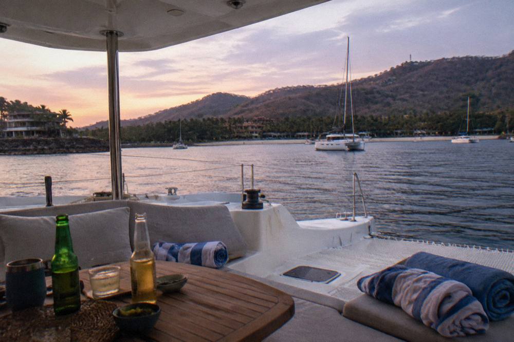 Private catamaran at anchor in a small bay with towels and drinks set out on deck