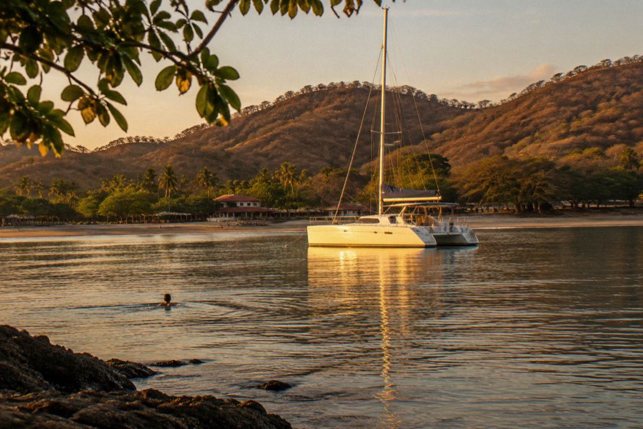 White catamaran anchored in a calm Pacific bay near Tamarindo at golden hour