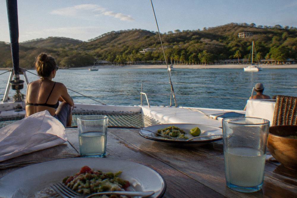 Open-air catamaran deck set with lunch plates and drinks in late afternoon