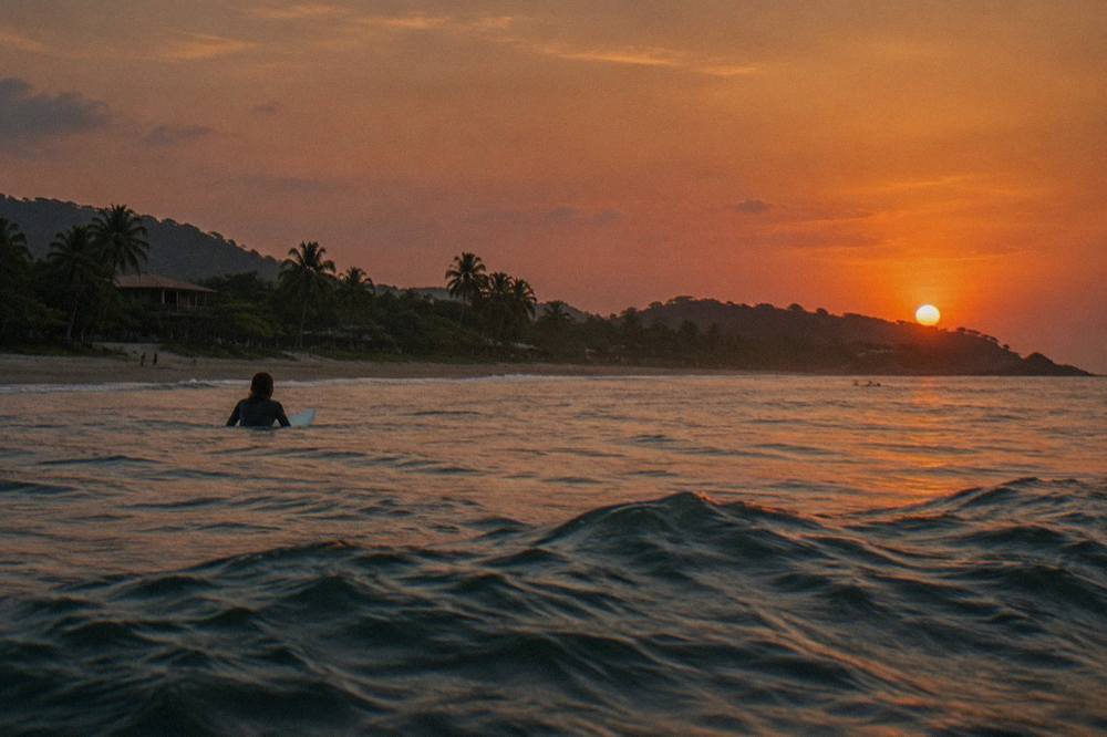 The sun low over the Pacific horizon seen from open water off Tamarindo with orange sky