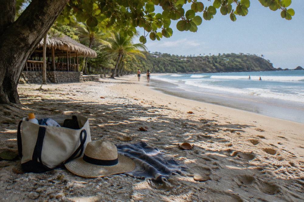 Beach bag with sunscreen, hat and towel beside a catamaran boarding point