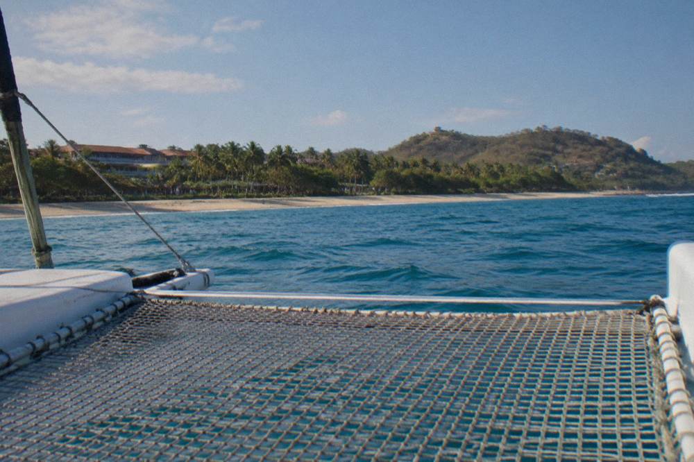 Calm catamaran trampoline netting over gentle blue Pacific swell